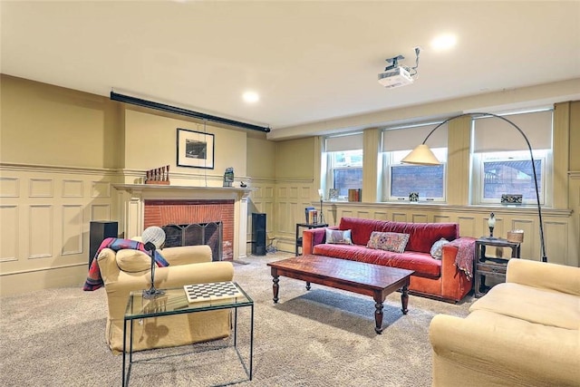 living room with wainscoting, carpet floors, a fireplace, and a decorative wall
