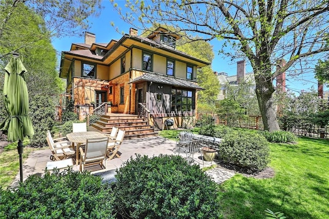 rear view of property with a lawn, fence, a chimney, and a patio area