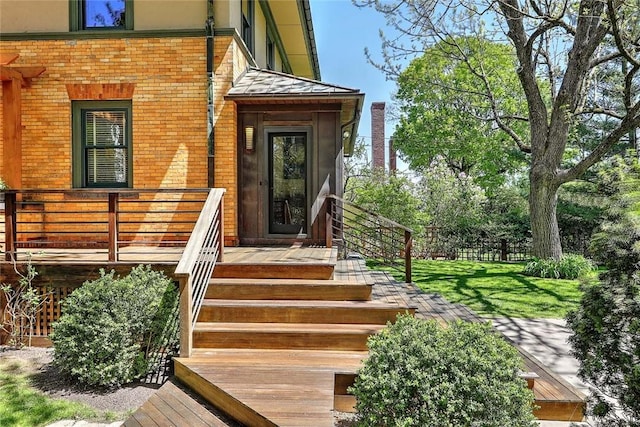 view of exterior entry featuring brick siding, stucco siding, and a yard