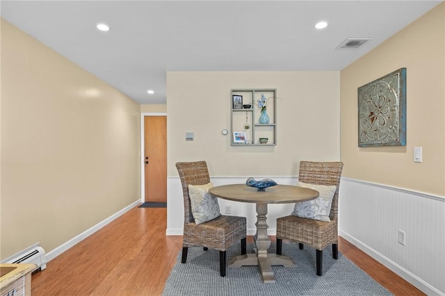 dining space featuring baseboard heating, a wainscoted wall, recessed lighting, wood finished floors, and visible vents