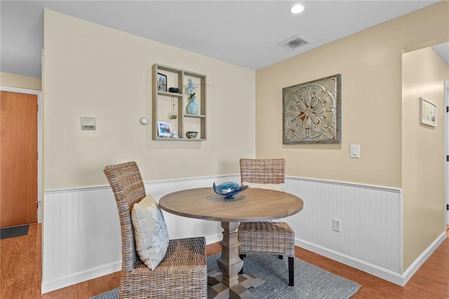 dining room featuring wood finished floors, a wainscoted wall, and visible vents