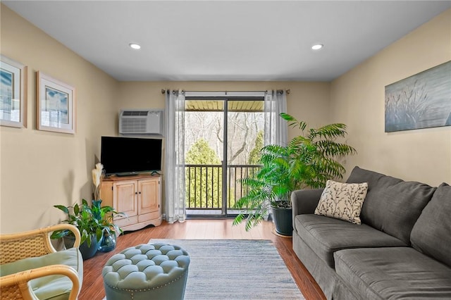 living room featuring an AC wall unit, recessed lighting, and wood finished floors