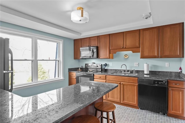 kitchen featuring stainless steel electric range oven, a sink, dishwasher, a breakfast bar area, and dark stone countertops