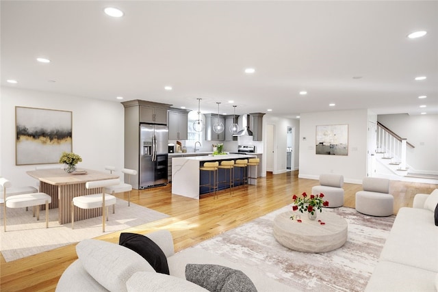 living room with recessed lighting, light wood-style floors, and stairs
