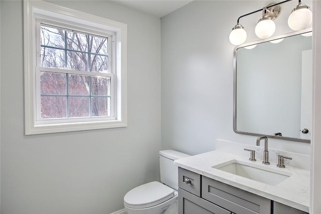half bath with a healthy amount of sunlight, vanity, and toilet