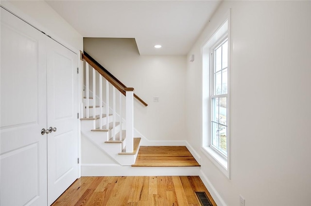 stairway with baseboards, recessed lighting, wood finished floors, and visible vents