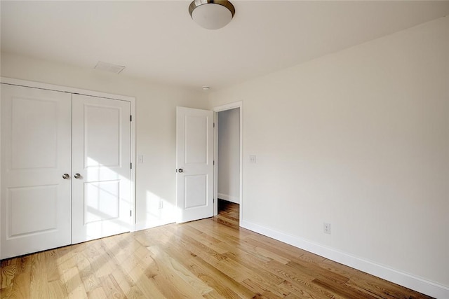 unfurnished bedroom featuring baseboards, a closet, and light wood-type flooring