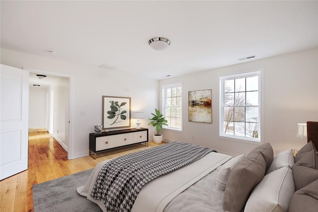 bedroom with light wood finished floors and visible vents