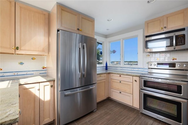 kitchen featuring stainless steel appliances, recessed lighting, light brown cabinetry, decorative backsplash, and light stone countertops
