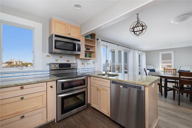 kitchen with a sink, a peninsula, stainless steel appliances, light stone countertops, and light brown cabinets