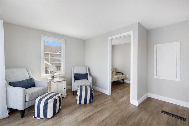 sitting room with baseboards, visible vents, and wood finished floors
