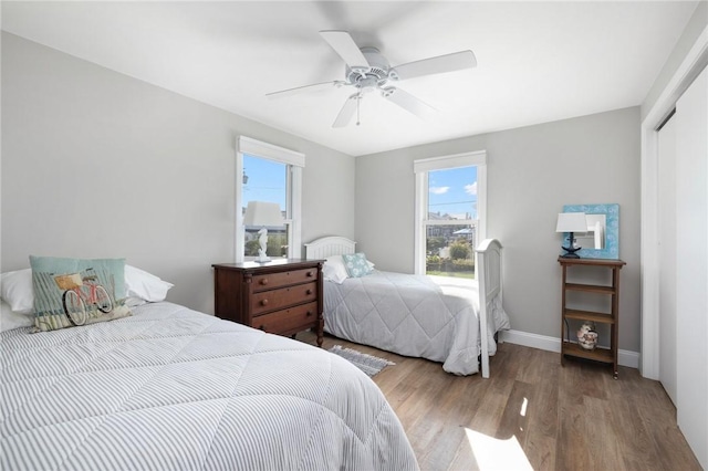 bedroom with a ceiling fan, multiple windows, a closet, and wood finished floors