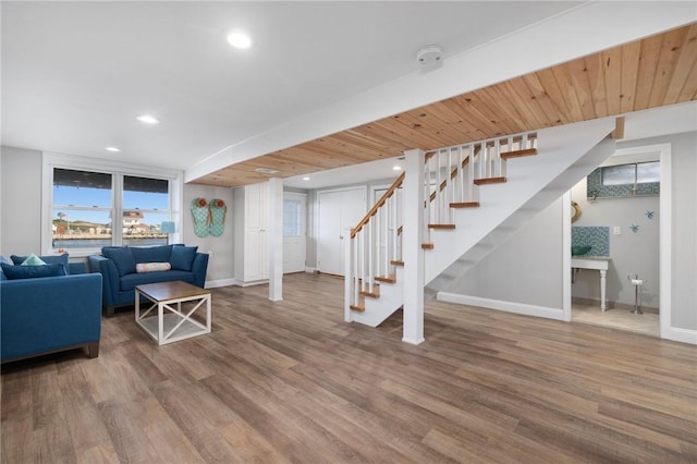 living room featuring baseboards, stairway, and wood finished floors