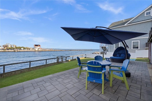 view of patio / terrace featuring a water view, outdoor dining area, and fence