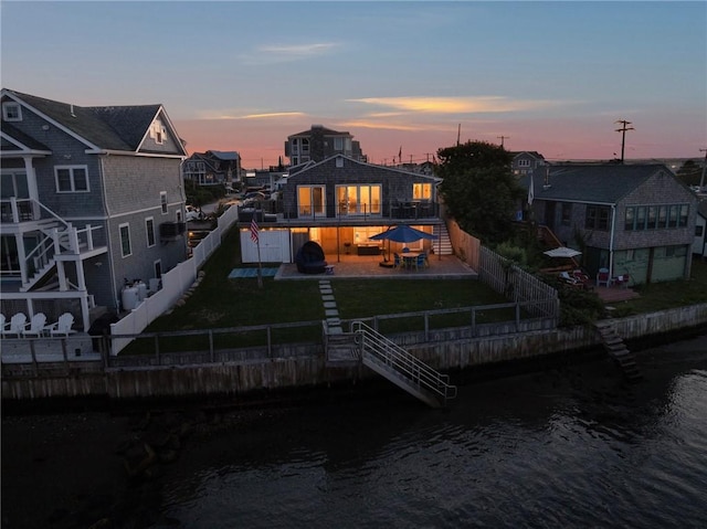 back of property with a yard, a patio, a water view, stairway, and a fenced backyard