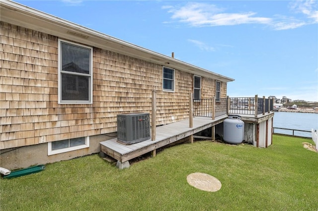 rear view of property with a yard, cooling unit, and a deck with water view