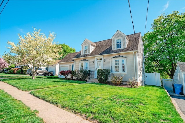 new england style home with an attached garage, fence, and a front lawn