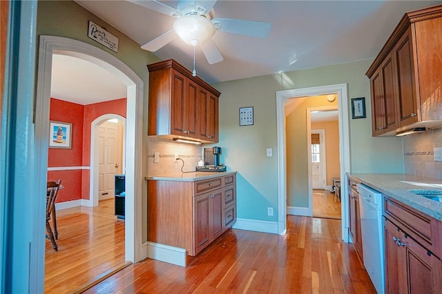kitchen with white dishwasher, a ceiling fan, backsplash, and light wood finished floors