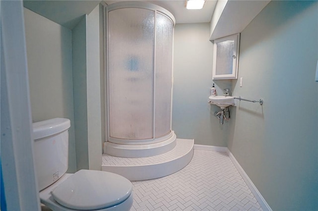 bathroom featuring toilet, baseboards, and a stall shower