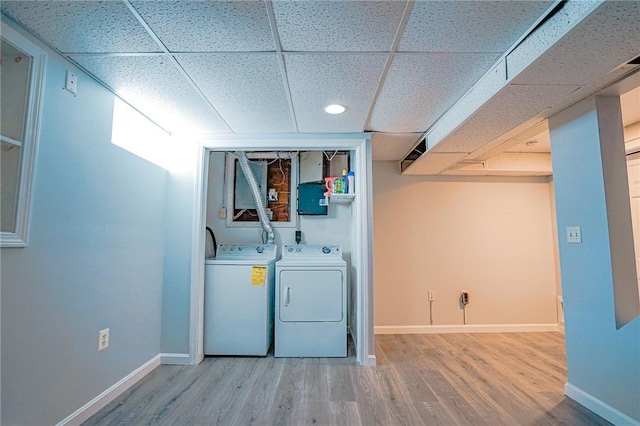 clothes washing area featuring baseboards, laundry area, washing machine and dryer, and light wood finished floors