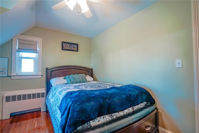 bedroom with wood finished floors, a ceiling fan, lofted ceiling, and radiator heating unit