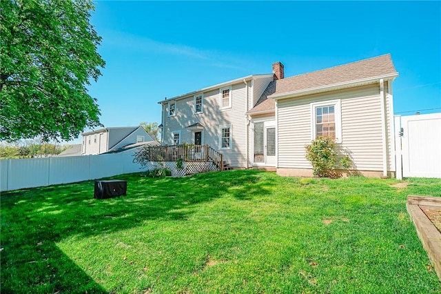 back of property with a lawn, fence, a chimney, and a deck
