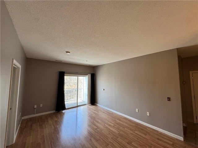 unfurnished room featuring a textured ceiling, baseboards, and wood finished floors