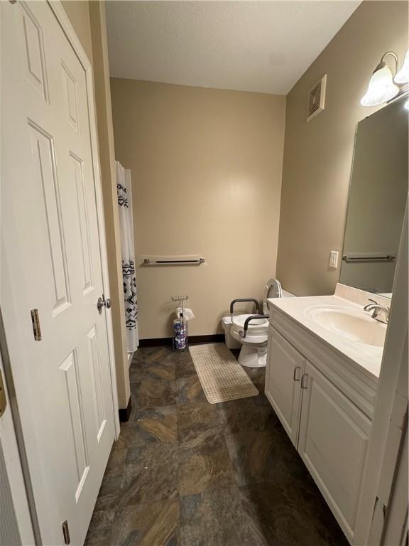 full bathroom with vanity, visible vents, toilet, baseboards, and stone finish floor