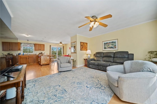 living room featuring light wood-style floors, ceiling fan, and ornamental molding