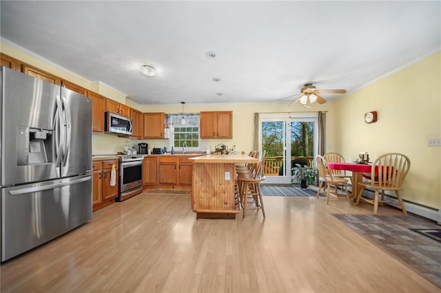 kitchen with light wood finished floors, light countertops, a kitchen breakfast bar, stainless steel appliances, and a ceiling fan