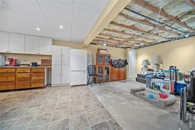basement featuring freestanding refrigerator and recessed lighting