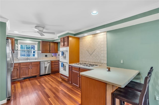 105 Quaker Dr, West Warwick, RI 02893 - kitchen with a sink, a peninsula, crown molding, backsplash, and appliances with stainless steel finishes