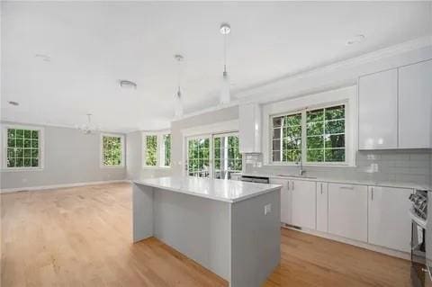 70 Shady Ln, Burrillville, RI 02859 - kitchen with a center island, light countertops, light wood-style flooring, white cabinetry, and tasteful backsplash
