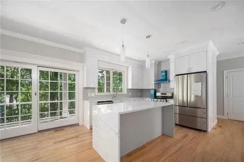 70 Shady Ln, Burrillville, RI 02859 - kitchen with appliances with stainless steel finishes, white cabinetry, light countertops, a center island, and light wood-type flooring