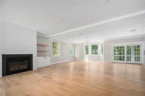 70 Shady Ln, Burrillville, RI 02859 - unfurnished living room with a glass covered fireplace, wood finished floors, healthy amount of natural light, ornamental molding, and baseboards