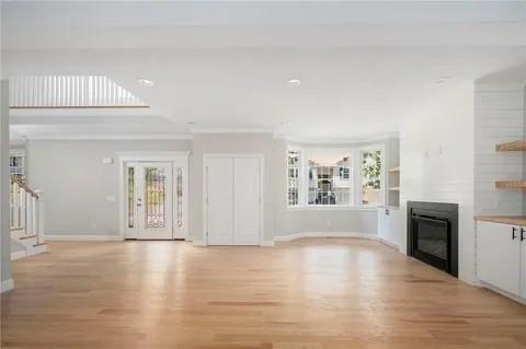 70 Shady Ln, Burrillville, RI 02859 - unfurnished living room with a glass covered fireplace, light wood-style floors, baseboards, stairway, and recessed lighting