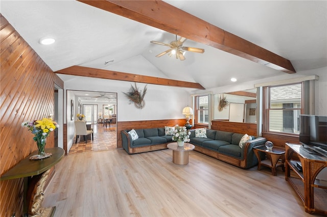 living room with light wood finished floors, ceiling fan, a wainscoted wall, and wooden walls