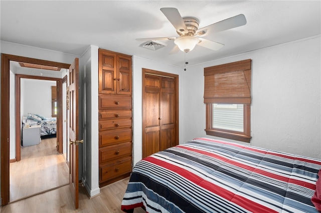 bedroom with a closet, light wood finished floors, ceiling fan, and visible vents