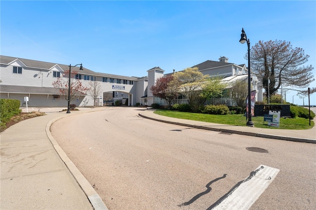 view of street featuring a residential view, sidewalks, curbs, and street lights