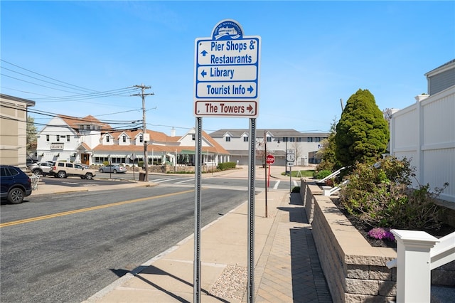 view of road featuring street lighting, curbs, traffic signs, sidewalks, and a residential view