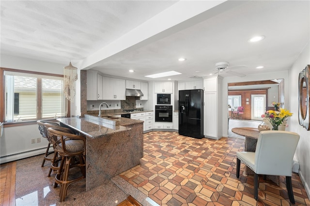 kitchen featuring a sink, a peninsula, a ceiling fan, a baseboard heating unit, and black appliances