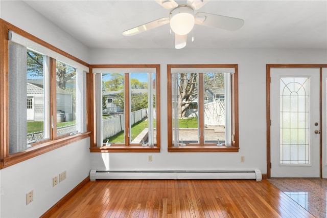 interior space with baseboard heating, baseboards, a wealth of natural light, and hardwood / wood-style floors