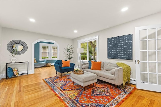 living area featuring baseboards, arched walkways, recessed lighting, and wood finished floors