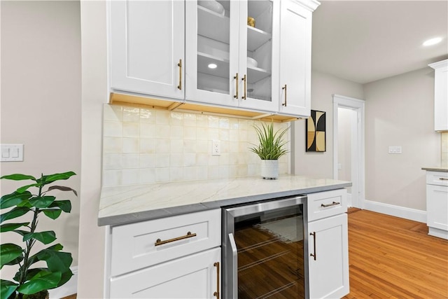 bar featuring beverage cooler, light wood-style flooring, baseboards, backsplash, and recessed lighting