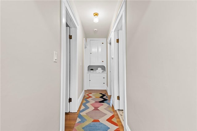 hallway with light wood-type flooring and baseboards