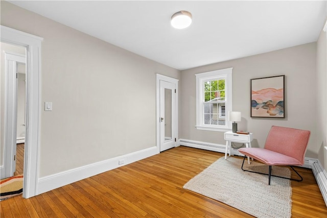 sitting room with a baseboard radiator, a baseboard heating unit, baseboards, and wood finished floors