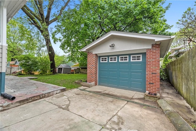 detached garage featuring fence and driveway