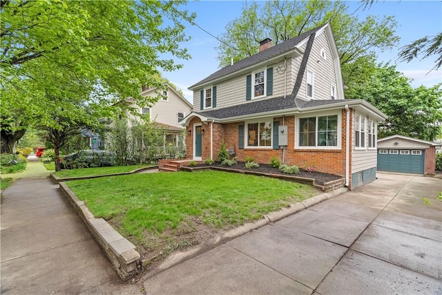 view of front of house with roof with shingles, a detached garage, brick siding, an outbuilding, and a front yard