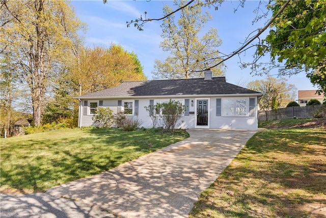 ranch-style home with concrete driveway, fence, a chimney, and a front yard
