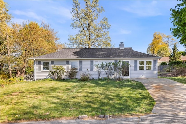 ranch-style house with fence, roof with shingles, a chimney, and a front lawn